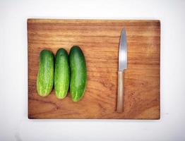 Cucumbers on a wooden cutting board and kitchen knife. photo