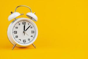 white clock on yellow background concept of time time is important to work photo