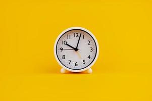 white clock on yellow background concept of time Time planning photo