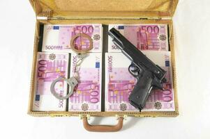 A briefcase with money, gun and handcuffs photo