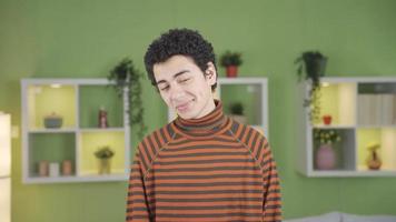 ritratto di bello adolescente ragazzo. un' comprensivo e bello ragazzo guardare a il telecamera a casa è sorridente e essere contento. Riccio capelli. video