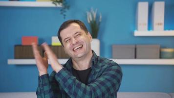 divertente e divertente uomo applaudire a casa sorridente. sorridente e battimani divertente e avendo divertimento uomo gode bene notizia. video