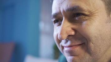 Portrait of respectful and understanding man smiling sadly. Happy and thoughtful man sitting at home alone thinking about life alone. video