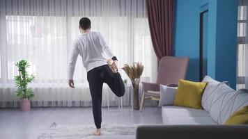 Young athletic man exercising at home for leg warm-ups before sports. Young athlete warming up and stretching at home, doing leg stretches, trying not to injure his body. Sport teacher. video