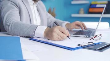 Close-up of business man's hands in modern office room.  Young businessman completing his work at the computer, taking notes, typing on the keyboard. video