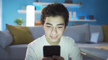 Portrait of a teenager using a smartphone. The young person using a smart phone alone at night is texting, doing research on the internet, surfing the media with social media. video