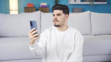 joven hombre mirando a el teléfono es decepcionado. joven hombre mirando a el teléfono es triste. obtiene malo noticias. video