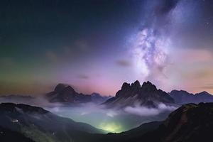 Milky Way over mountains in fog at night in summer. Landscape with foggy alpine mountain valley photo