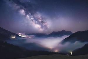 Milky Way over mountains in fog at night in summer. Landscape with foggy alpine mountain valley photo