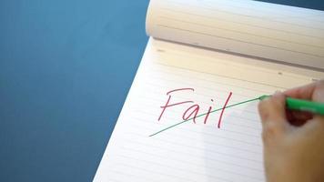 Fild text with a hand with a red pen and crossed out with a green pen on the notebook, Success message by hand with a green pen below the fail video