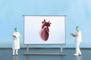 miniatura gente. médico es diagnosticando corazón enfermedad en pantalla foto