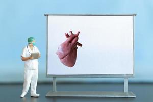 Miniature people. Doctor is diagnosing heart disease on screen photo