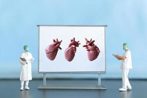 miniatura gente. médico es diagnosticando corazón enfermedad en pantalla foto