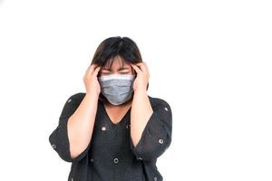 Portrait of asian woman wearing a face mask and holding head because of a headache in studio on isolated white background. Concept of concern, protection and quarantine coronavirus photo
