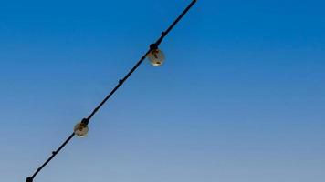 Group of Light bulbs hanging on wires against on blue sky. photo
