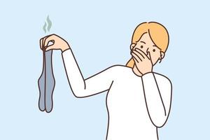 Young woman holding dirty stinky socks in hands disgusted by smell. Girl with smelly stockings irritated repulsed with dirt. Vector illustration.