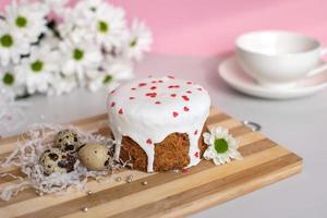 Easter cake with white icing with quail eggs and white flowers. white cup photo