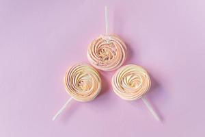 Pink round sweet meringues with decor lie on a pink background photo