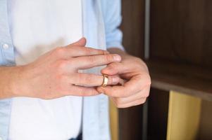 un negocio hombre elimina un oro Boda anillo desde su Derecha mano foto