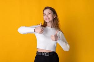 Young caucasian happy woman showing thumbs up on bright yellow background photo