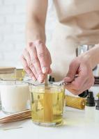 closeup of woman setting the wooden wick into handmade candle photo