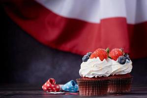 Sweet cupcakes with blueberries and strawberry over USA flag background photo