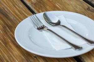 tenedor y cuchara con plato blanco sobre mesa de madera foto