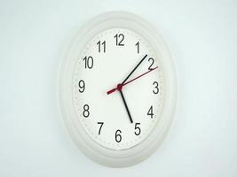 Front view of a white clock displayed on a white wall, the numbers are clear. video