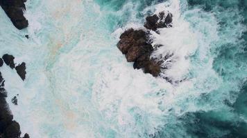 Overhead View Of Foamy Waves Breaking On Outcrops In Caion Beach, Coruna Spain. Aerial Topdown video