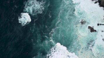 dar roterend over- krachtig golven crashen Aan rotsachtig kustlijn met schuimend oppervlakken. antenne schot video