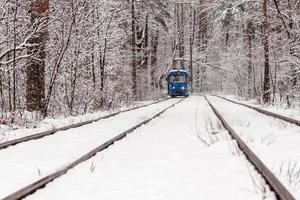 An old tram moving through a winter forest photo