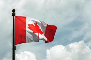 bandera de Canadá en asta de bandera flotante en el cielo foto