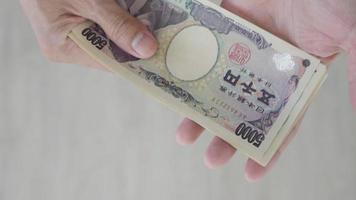 japonés yen dinero. cerca arriba de el japonés yen en mano. moneda de Japón ese es usado a cambiar, comprar, vender, acumular, invertir, financiero, intercambiar tasa, valor, contabilidad, internacional intercambiar video