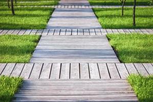 Wooden garden paths - walkways of natural wood planks among green grass and trees photo