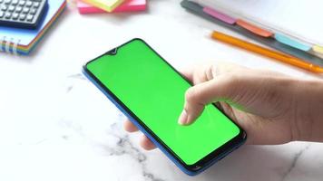 hoog hoek visie van Mens gebruik makend van mobiel slim telefoon met groen scherm video