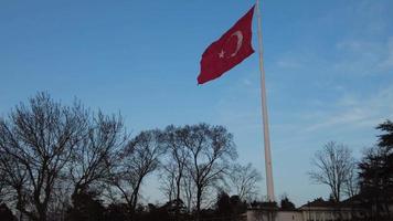 turc drapeau agitant dans le ciel, dans de face de une bleu Contexte video