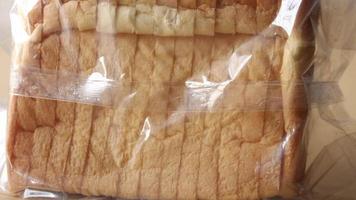 dichtbij omhoog van vers brood in een plastic pakket Aan tafel video