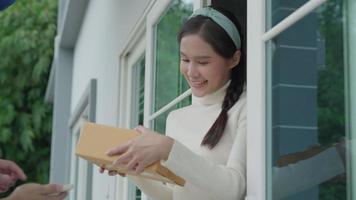 Happy smiling woman receives boxes parcel from courier in front house. Delivery man send deliver express. online shopping, paper containers, takeaway, postman, delivery service, packages video