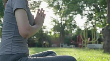 mujer practicando meditar en el parque. mujer asiática haciendo ejercicios por la mañana. equilibrio, recreación, relajación, calma, buena salud, feliz, relax, estilo de vida saludable, reducir el estrés, paz, actitud. video