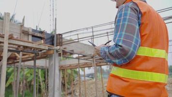 el inspector o ingeniero está inspeccionando la construcción y el aseguramiento de la calidad de la nueva casa usando una lista de verificación. ingenieros o arquitectos o contratistas trabajan para construir la casa antes de entregársela al propietario video