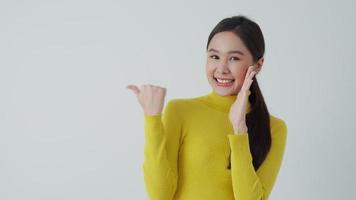 Portrait asian beautiful girl pointing blank space isolated background. Happy woman pointing on something. young female standing pointing finger sideways, billboard, introduction, advertisement, space video