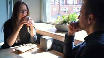 Young couple talking and drinking coffee in cafe video