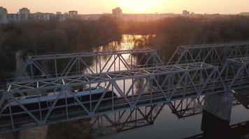 vue de le la taille de le chemin de fer pont sur lequel le train est qui passe à le coucher du soleil video