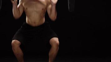 Man is doing exercises with a barbell, training on a black background in the studio. Half body in frame video