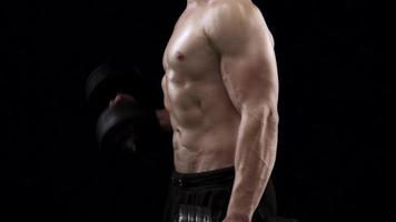 Man is doing exercises with a barbell, training on a black background in the studio video