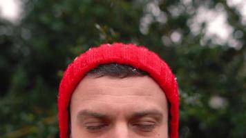 ritratto di un' uomo nel un' rosso berretto nel nevoso tempo metereologico all'aperto video