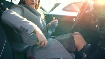 Female hand fastening car safety seat belt while sitting inside of vehicle before driving video