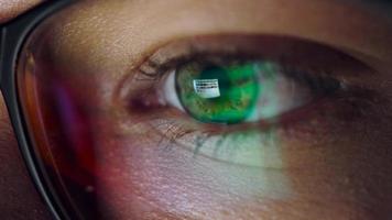 Woman in glasses looking on the monitor and surfing Internet. The monitor screen is reflected in the glasses video