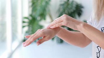 fechar-se mulher é mãos hidratante mãos com creme em monstera borrado fundo. mão massagem. cosmetologia, mão Cuidado, spa cosméticos, beleza conceito. video