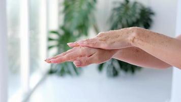 Close-up woman is hands with coffee massage scrub on monstera blurred background. Cosmetology, hand care, spa cosmetics, beauty concept. video